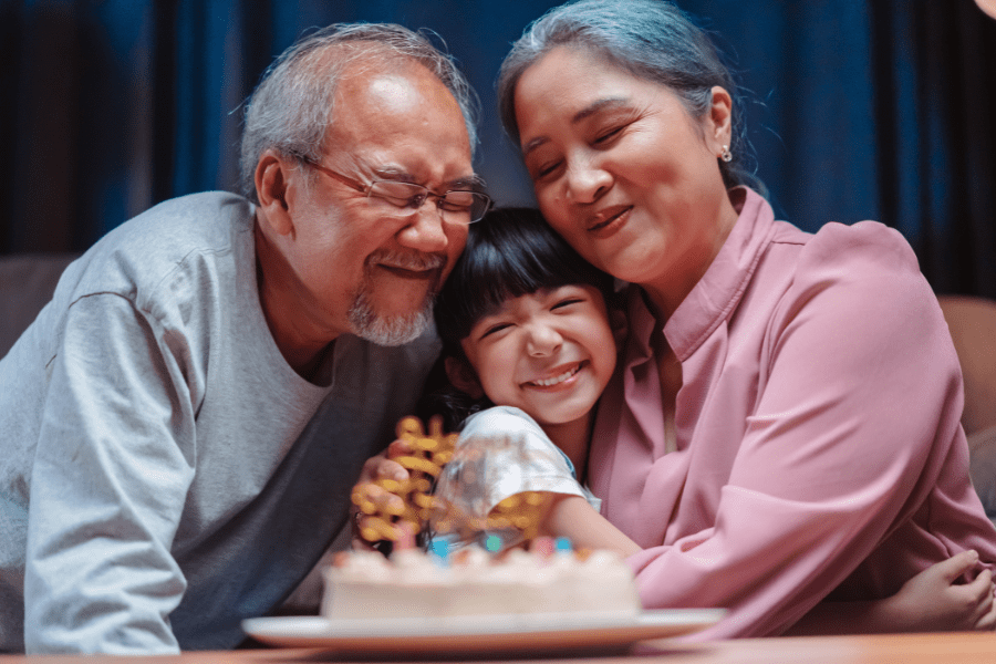 A grandpa and grandma squeeze their granddaughter on her birthday.