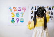 Little girl in pig tails points to letters on a chart.