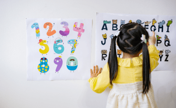 Little girl in pig tails points to letters on a chart.