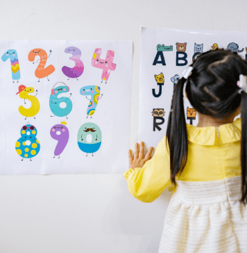 Little girl in pig tails points to letters on a chart.