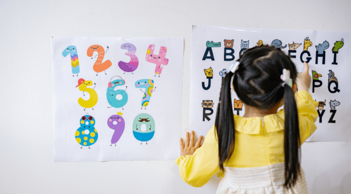 Little girl in pig tails points to letters on a chart.