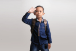 Kindergarten boy waves a salute goodbye as he wears a backpack and heads to school.