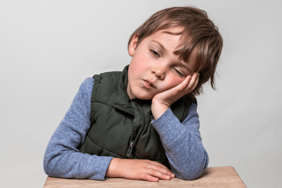 Kindergarten boy falls asleep at this desk.