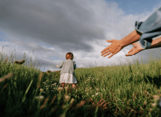 Toddler girl runs away from her mother in a meadow.