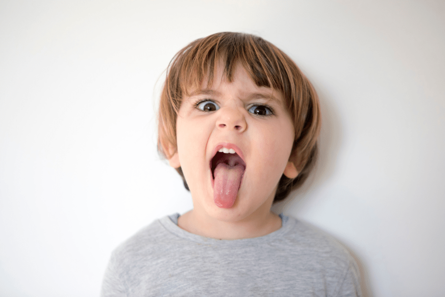 Little boy makes a silly face with his tongue sticking out.