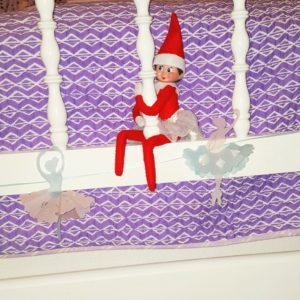 Elf on the shelf leaves paper snowflakes and ballerinas in a child's bedroom.