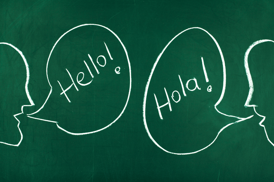 Chalkboard with talking bubbles that say "Hello!" and "Hola!" to raise a bilingual child.