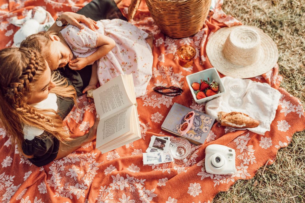 Mom reading to daughter on a picnic blanket