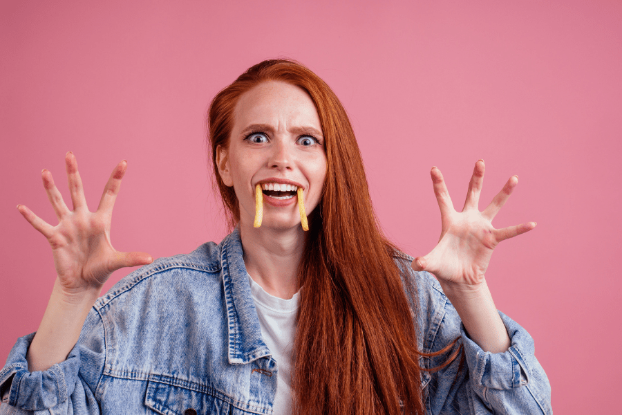 Silly woman looks spooky with french fries for fangs