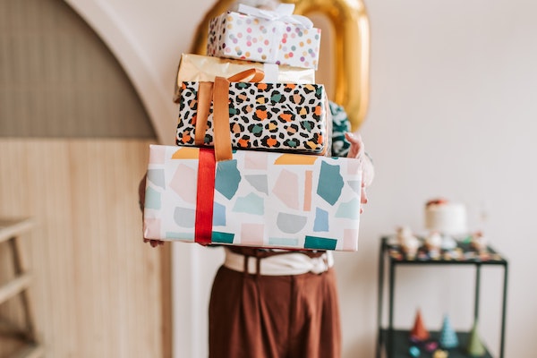 woman holding stack of wrapped gifts, best teacher gifts according to teachers