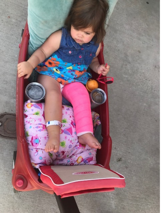 toddler in a leg cast in a wagon