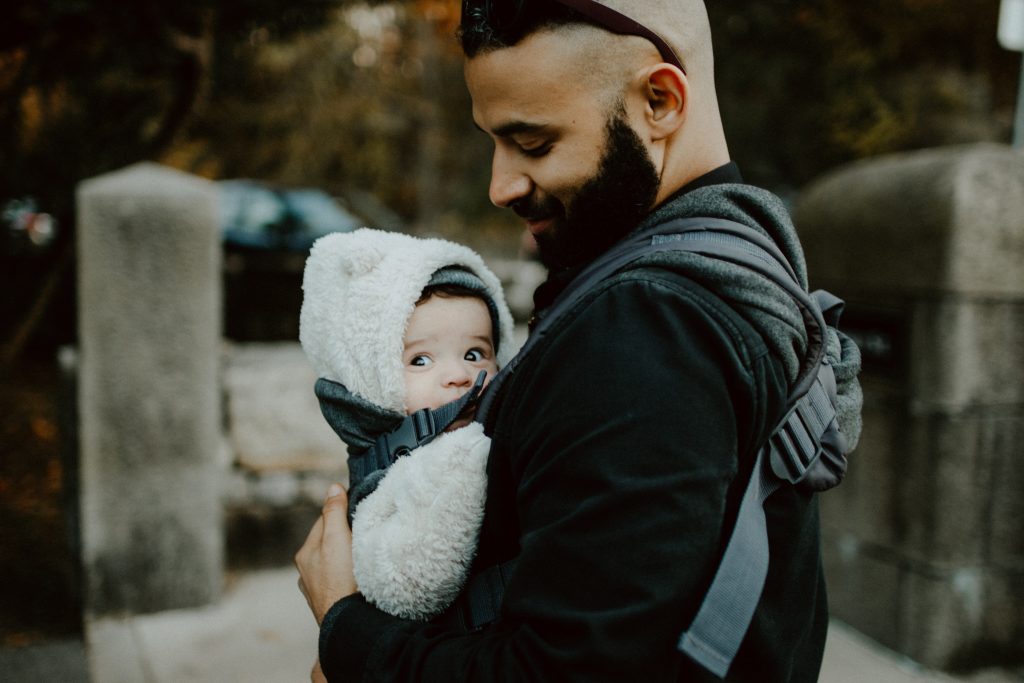 Dad gazing down at baby in carrier, benefits of babywearing