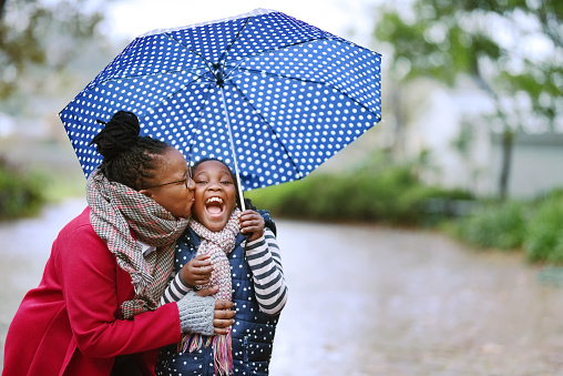 mom kissing daughter's cheek under umbrella in the rain, Dallas weather tracker