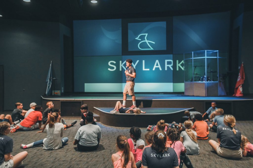 group of kids listening to a counselor speak at Camp Skylark, an affordable Dallas summer camp