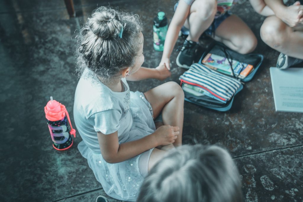 child sitting with friends at Camp Skylark, an affordable Dallas summer camp