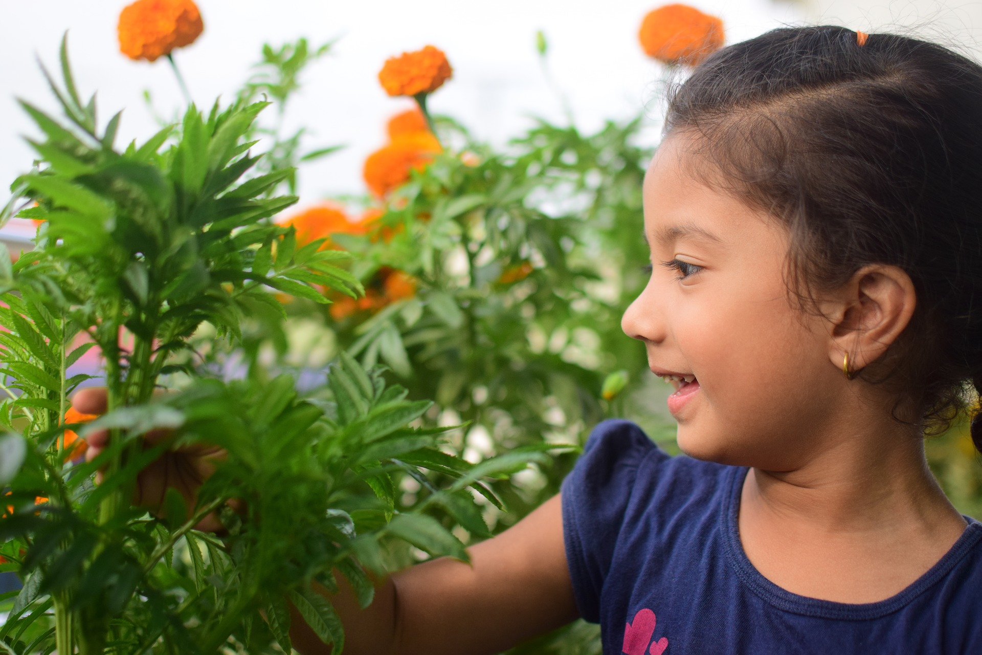 Girl smiling at flowers, kid-friendly Earth Day activities