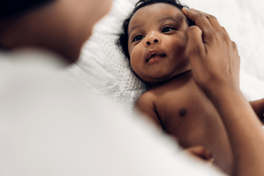 Mother stroke's newborn's head as baby stares up at her.