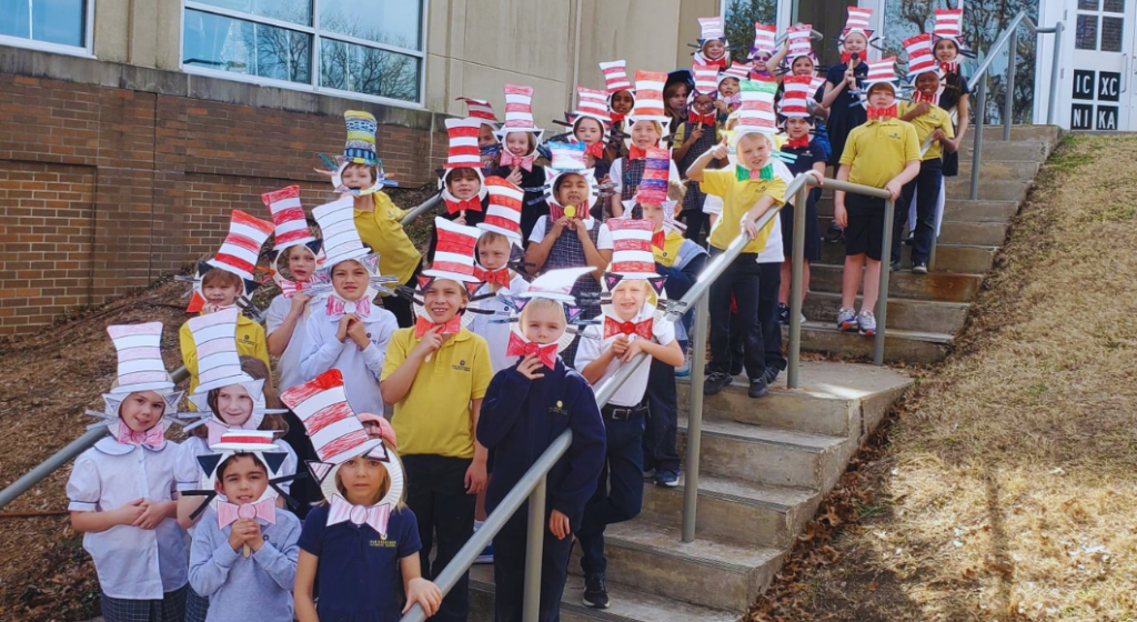Large group of students standing outside on the steps of Our Redeemer wearing paper Cat in the Hat top hats. Our Redeemer is a Christian private school in Dallas