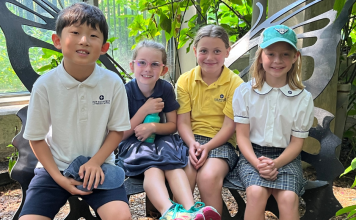 four students of Our Redeemer Lutheran School smiling while seated on a butterfly-shaped bench