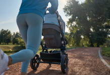 A mom pushes a baby stroller on her run outside on a running path.