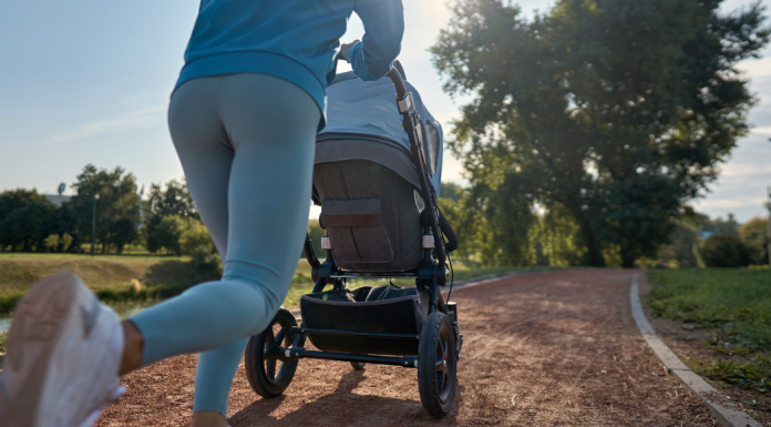 A mom pushes a baby stroller on her run outside on a running path.