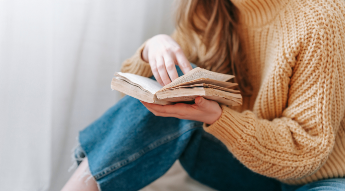 A woman holds a book in her hands reading.