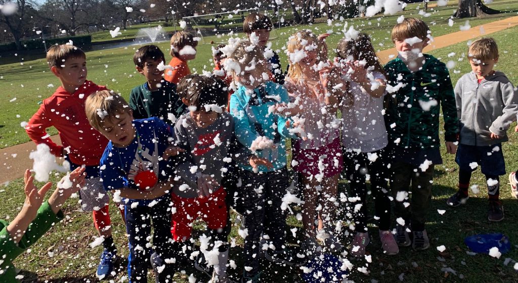 group of children outside with lots of foam in the air around them