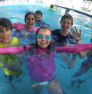 group of children smiling in a swimming pool at cooper aerobics summer day camp