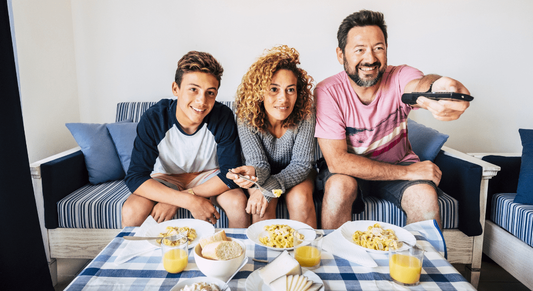 A family eats a meal while bing-watching tv.