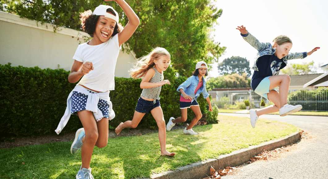 Happy girls jump off curb onto a street.