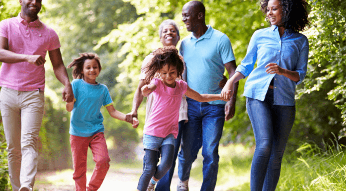 A family holds hands and walks on a trail outside.