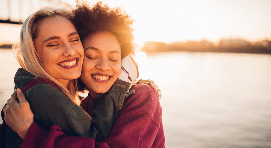 Two women hugging and smiling.