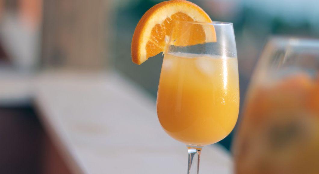 A mimosa in a glass with orange slice garnish