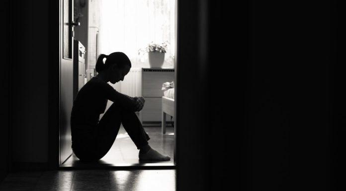 Woman sits on floor by yourself in a dark room.