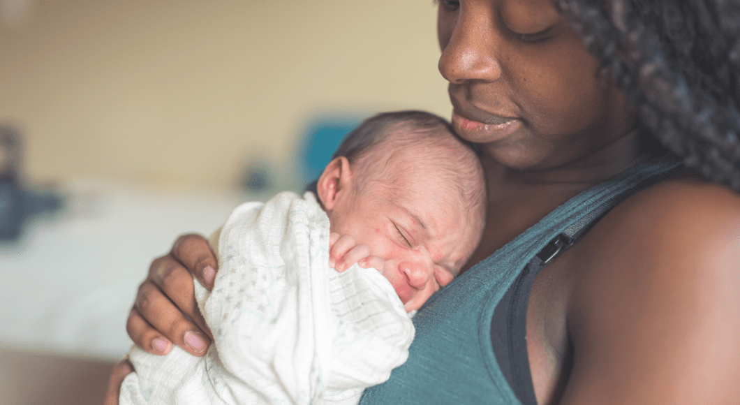 A new mom holds her infant on her chest.