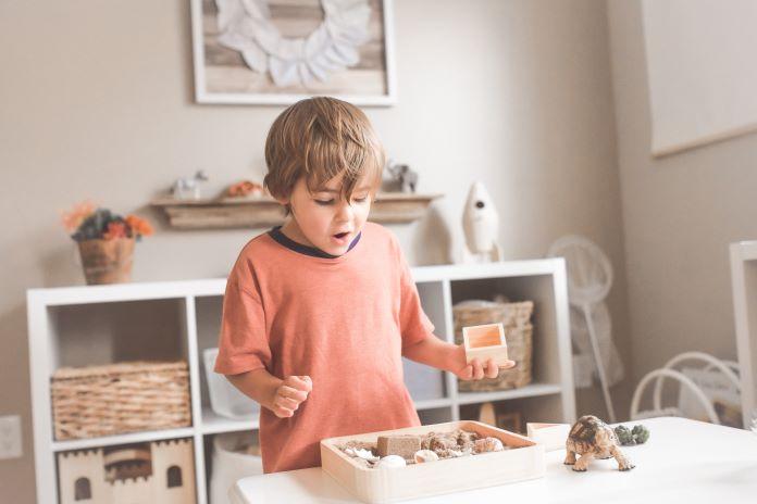 Toddler boy plays with wooden toys inside.