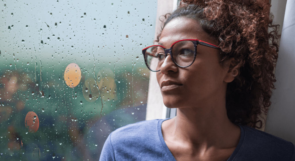 Sad woman looks out the window on a rainy day.