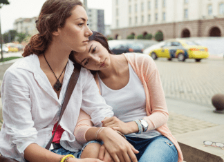 A woman leans her head on her friend's shoulder.