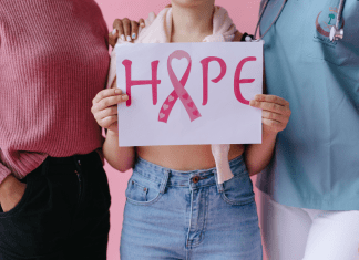 Two people stand next to a person holding a sign that says hope for breast cancer.