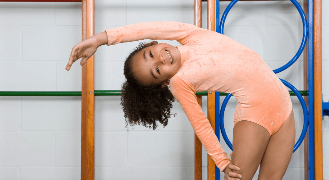 A girl in a gymnastics leotard stretches to the side.