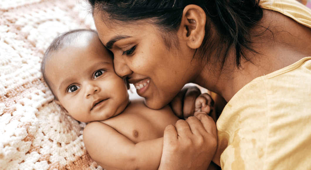 A Latina mom snuggles her baby boy infant.