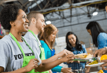 A woman helps at a soup kitchen wearing a green apron.