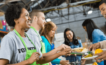 A woman helps at a soup kitchen wearing a green apron.