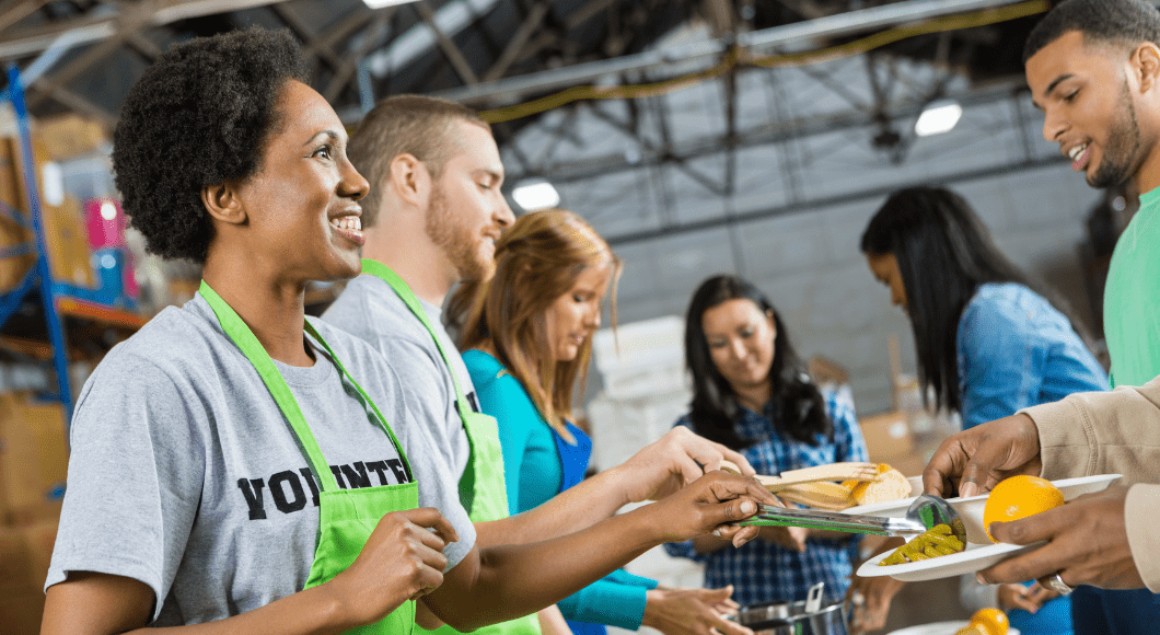 A woman helps at a soup kitchen wearing a green apron.