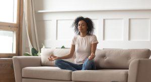 Woman meditates on the couch during her morning ritual.