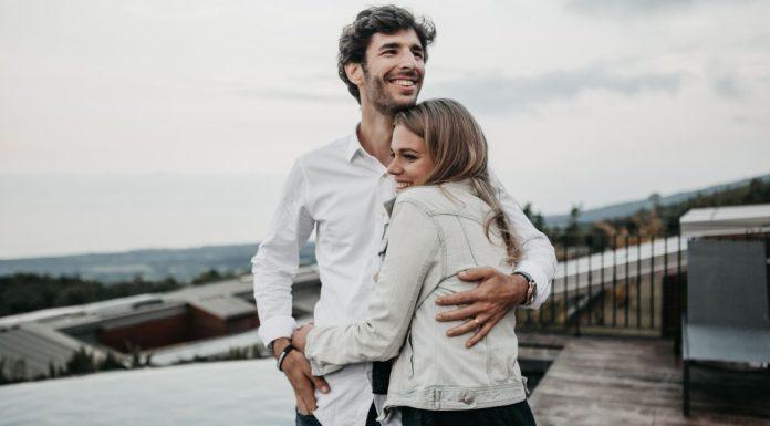 A young couple hug each other and smile.