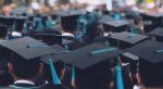 High school graduates sit in their caps and gowns during a graduation ceremony.