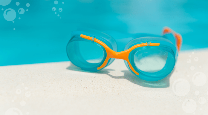 Swim goggles sitting on the side of a pool