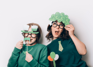 A mom and child try on silly St. Patrick's Day-themed photobooth props.