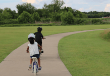 Two children riding bicycles on a paved path.